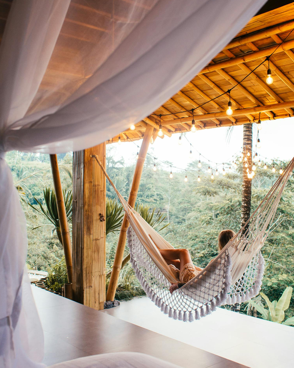 A photo of a traveler relaxing in a hammock surrounded by lights overlooking the forest